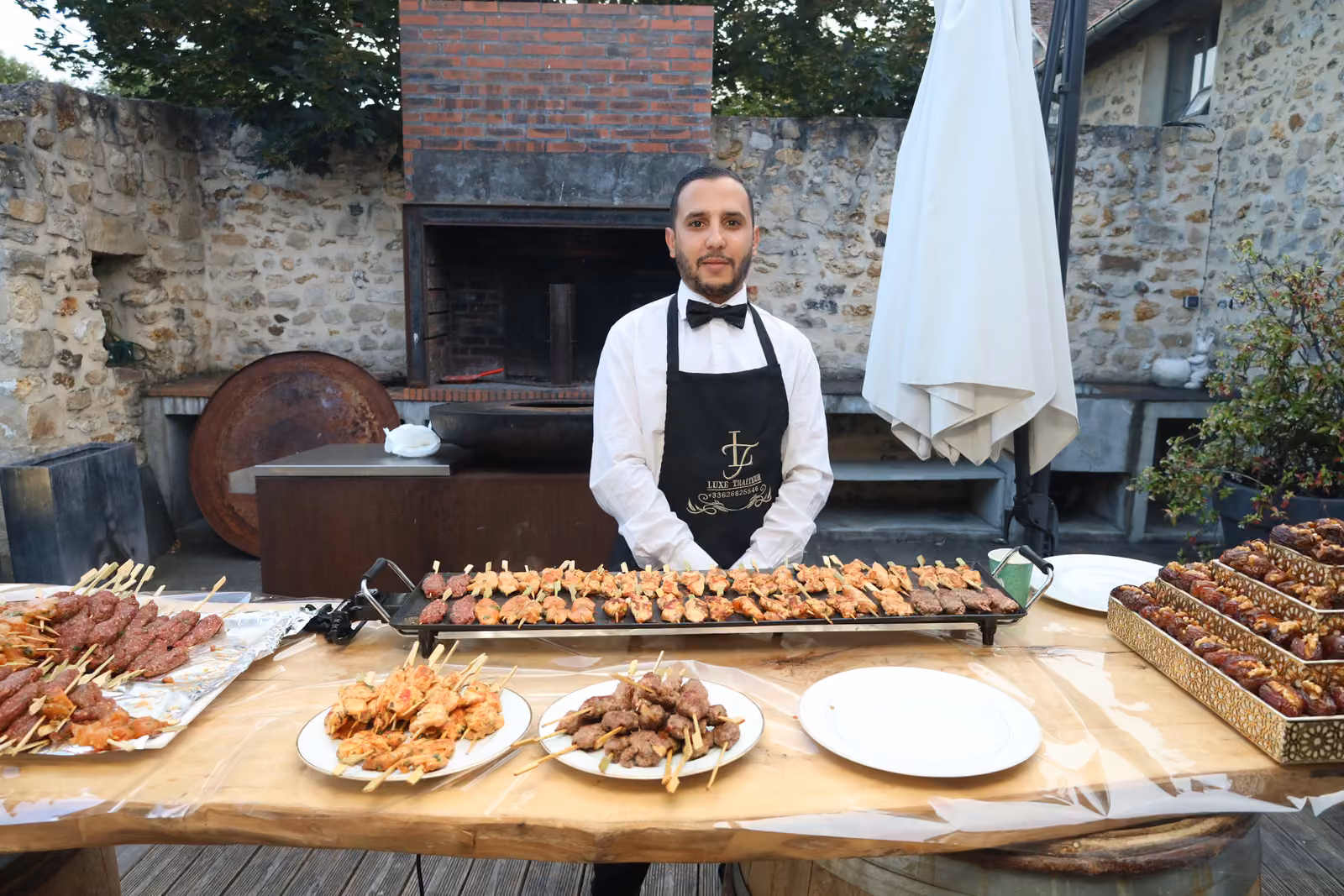 Atelier plancha au cocktail Serveur en tablier derrière un atelier plancha de brochettes de poulet et de kefta en extérieur