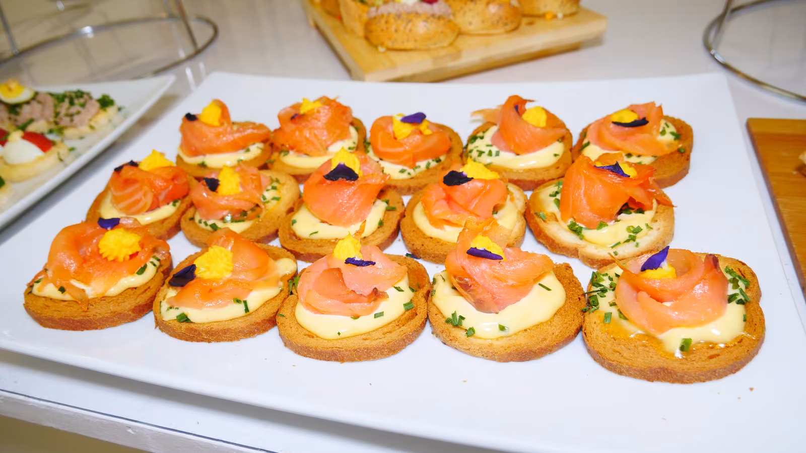 Blinis au saumon fumé Blinis au saumon fumé, crème et fleurs comestibles sur un plat blanc