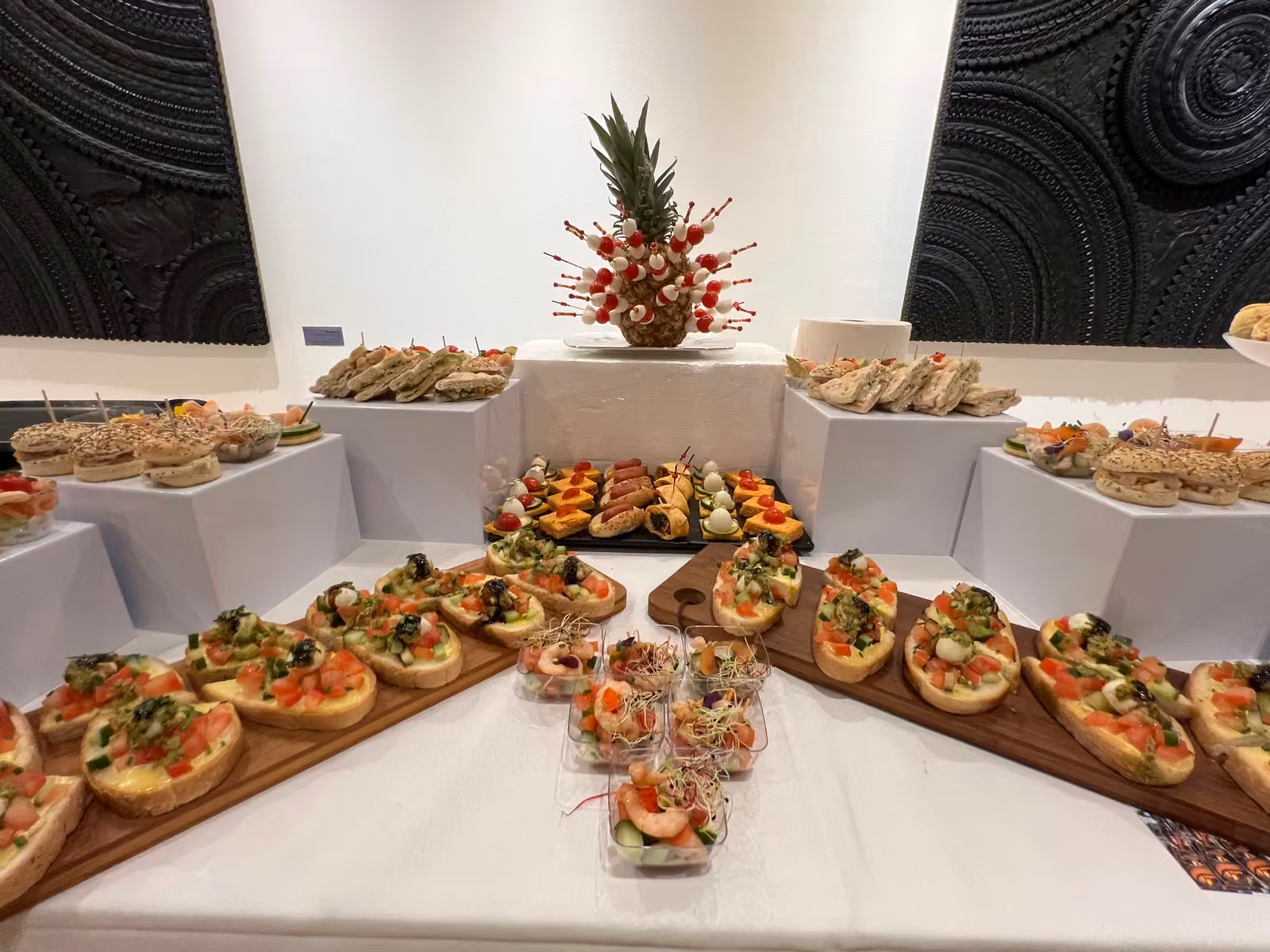 Buffet dînatoire et ananas décoré Buffet dînatoire en salle : pyramide d'ananas décorée, canapés sur planches et verrines de crevettes