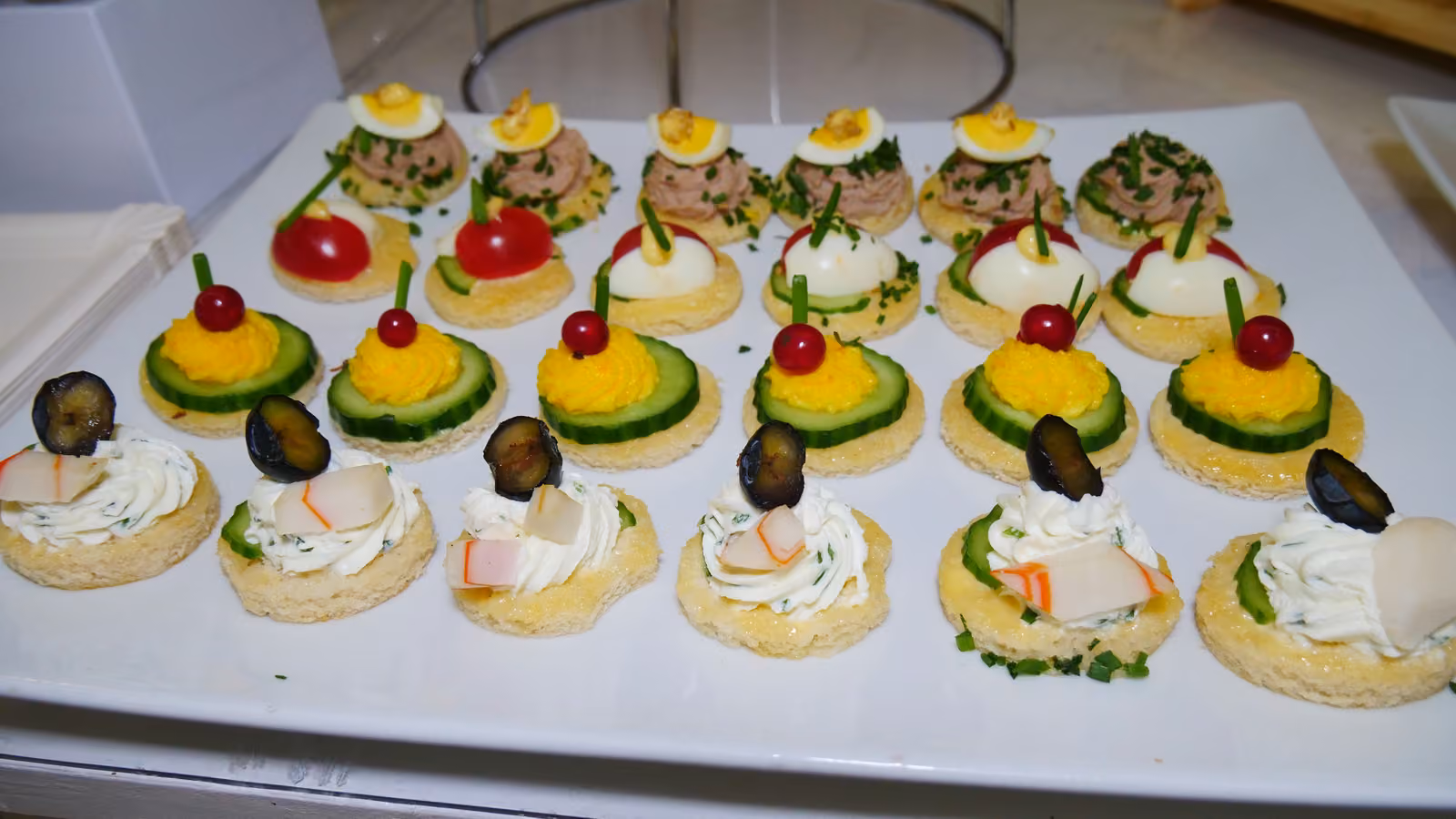 Canapés œuf mimosa et thon Canapés ronds à l'œuf mimosa, au thon et aux légumes sur un plat blanc