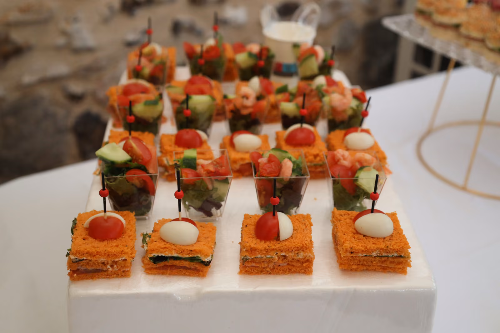 Canapés et verrines du cocktail Canapés à la tomate et à l'œuf de caille, verrines de légumes et brochettes sur un buffet blanc