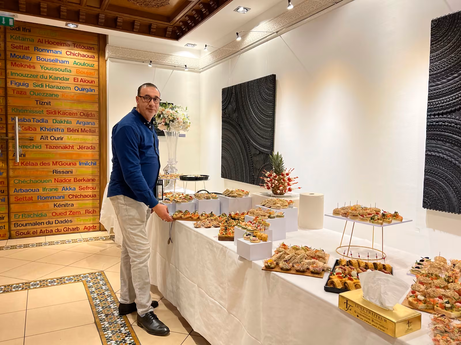 Le chef et le buffet dînatoire Chef traiteur en chemise bleue devant un buffet dînatoire dressé dans une salle de réception