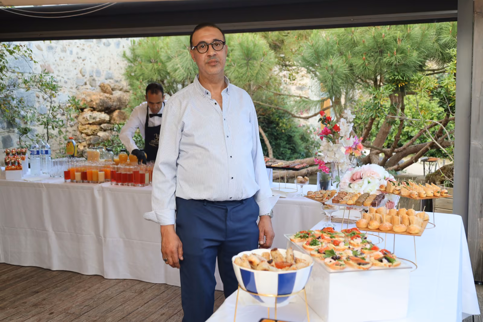 Le chef devant le buffet Chef traiteur en chemise blanche debout devant le buffet du cocktail en terrasse