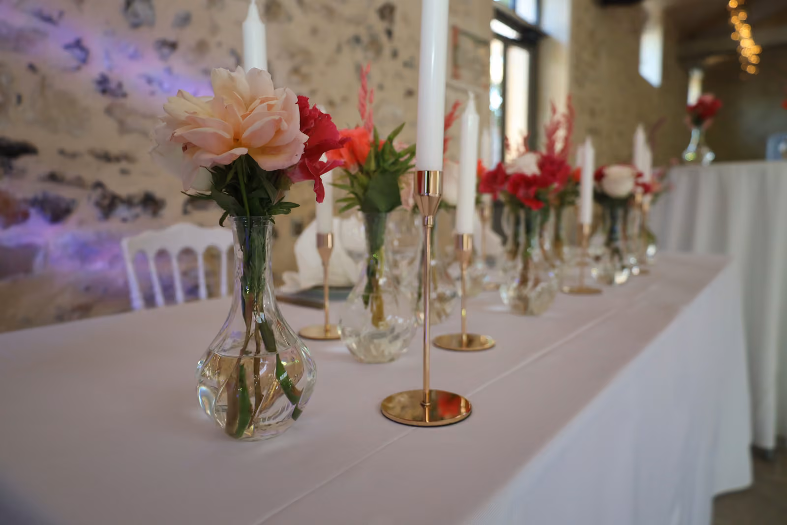 Détail fleuri d'une table de mariage Détail d'une table de mariage : pivoine pêche en vase boule, chandelier doré et bougie blanche