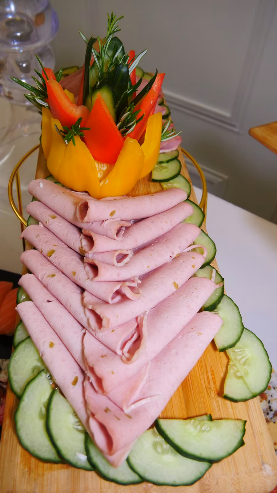 Jambon en éventail Tranches de jambon roulées en éventail, décor de poivron et rondelles de concombre sur planche