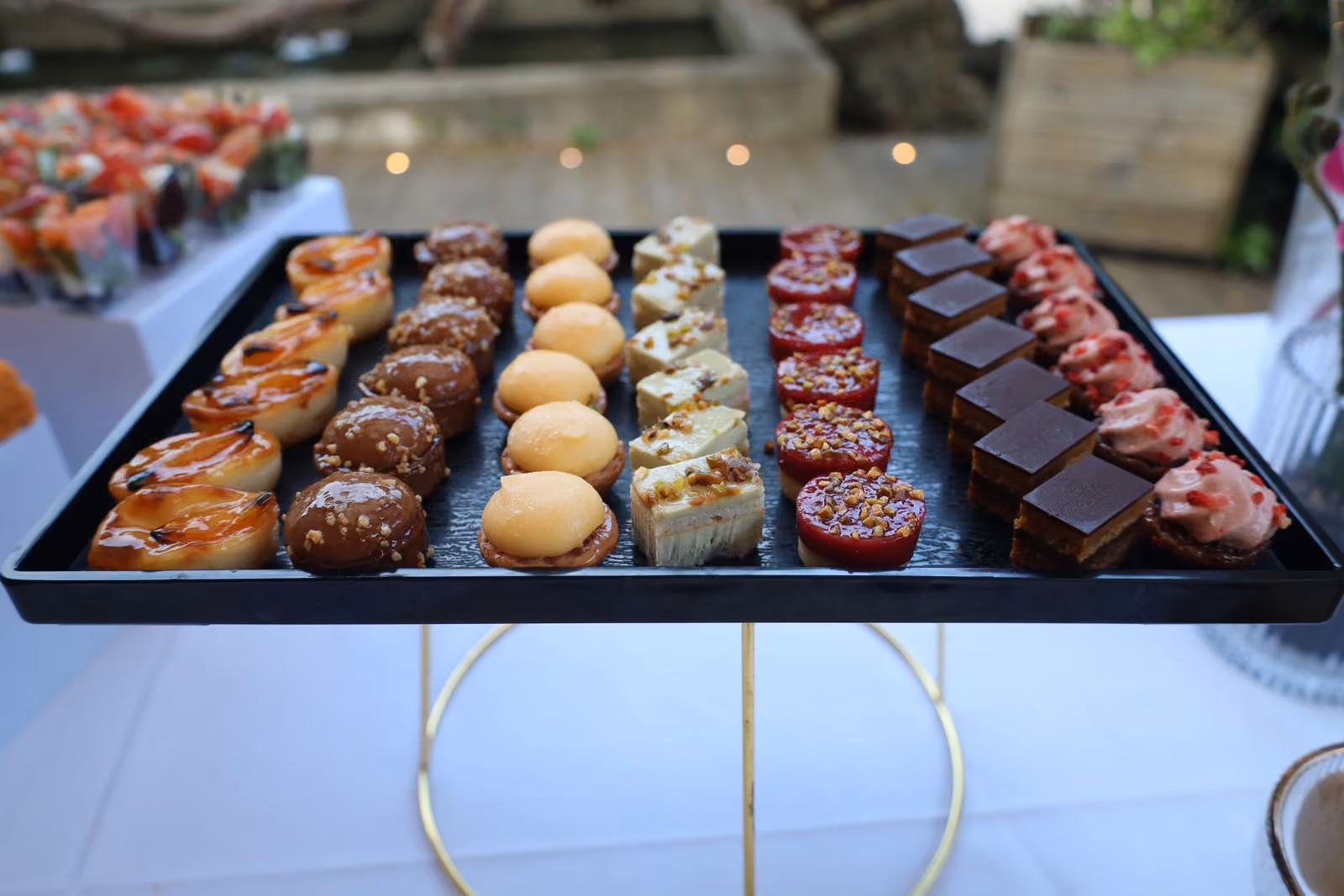 Mignardises et carrés au chocolat Plateau noir de mignardises : tartelettes, choux, carrés au chocolat et bouchées aux fruits rouges