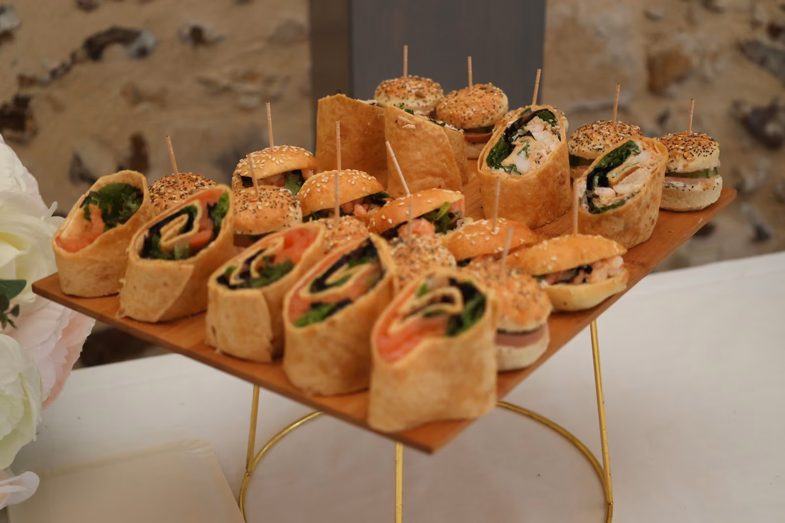 Mini-burgers et wraps au saumon Plateau en bois de mini-burgers au sésame et wraps au saumon sur un présentoir doré