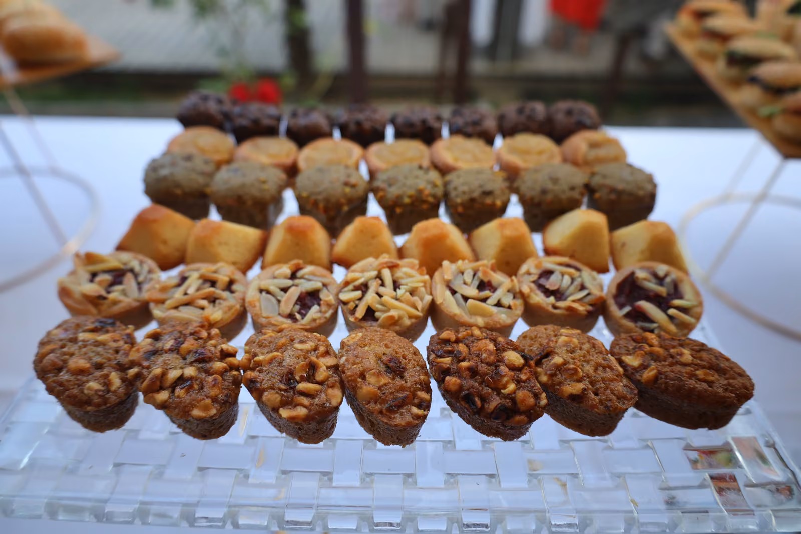 Mini-cakes et financiers Mini-cakes, financiers aux pignons et tartelettes alignés sur un plateau en verre