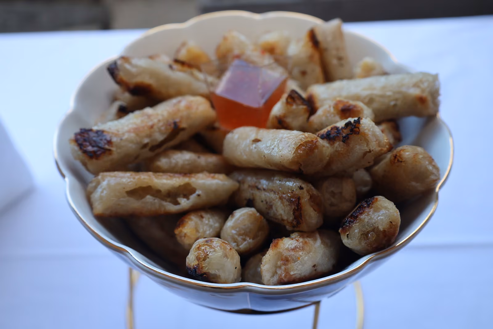 Nems grillés et sauce aigre-douce Coupe de nems grillés servis avec une sauce aigre-douce sur un présentoir doré