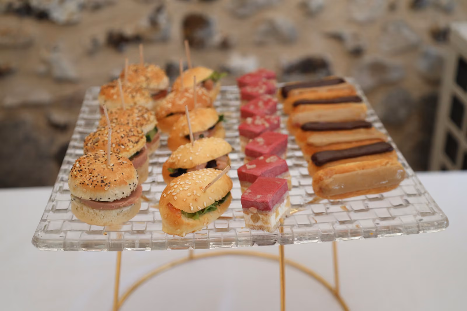 Mini-burgers et éclairs Plateau en verre de mini-burgers, gâteaux roses et éclairs au café pour un cocktail