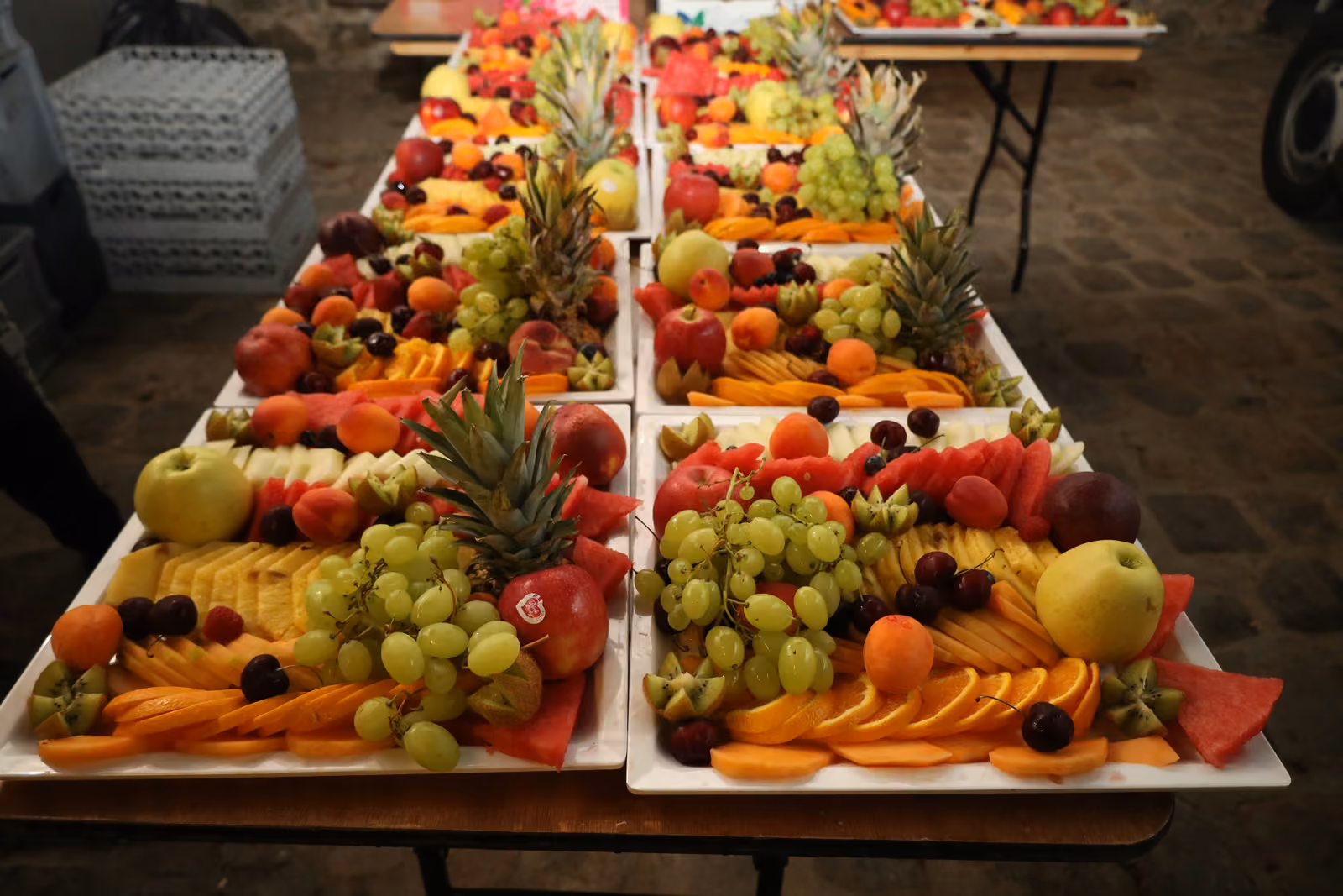 Plateaux de fruits frais Rangées de plateaux de fruits frais découpés : raisin, ananas, orange, pomme et pastèque