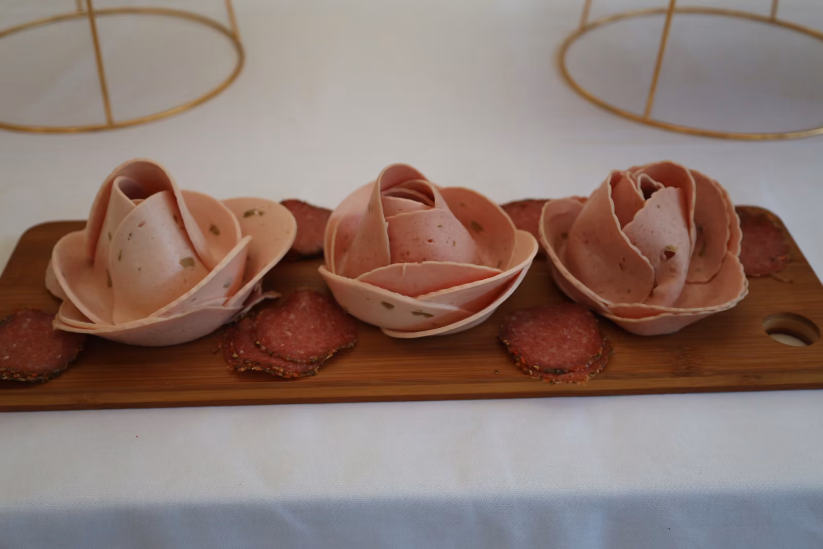 Roses de jambon sur planche Roses de jambon et rondelles de saucisson disposées sur une planche en bois