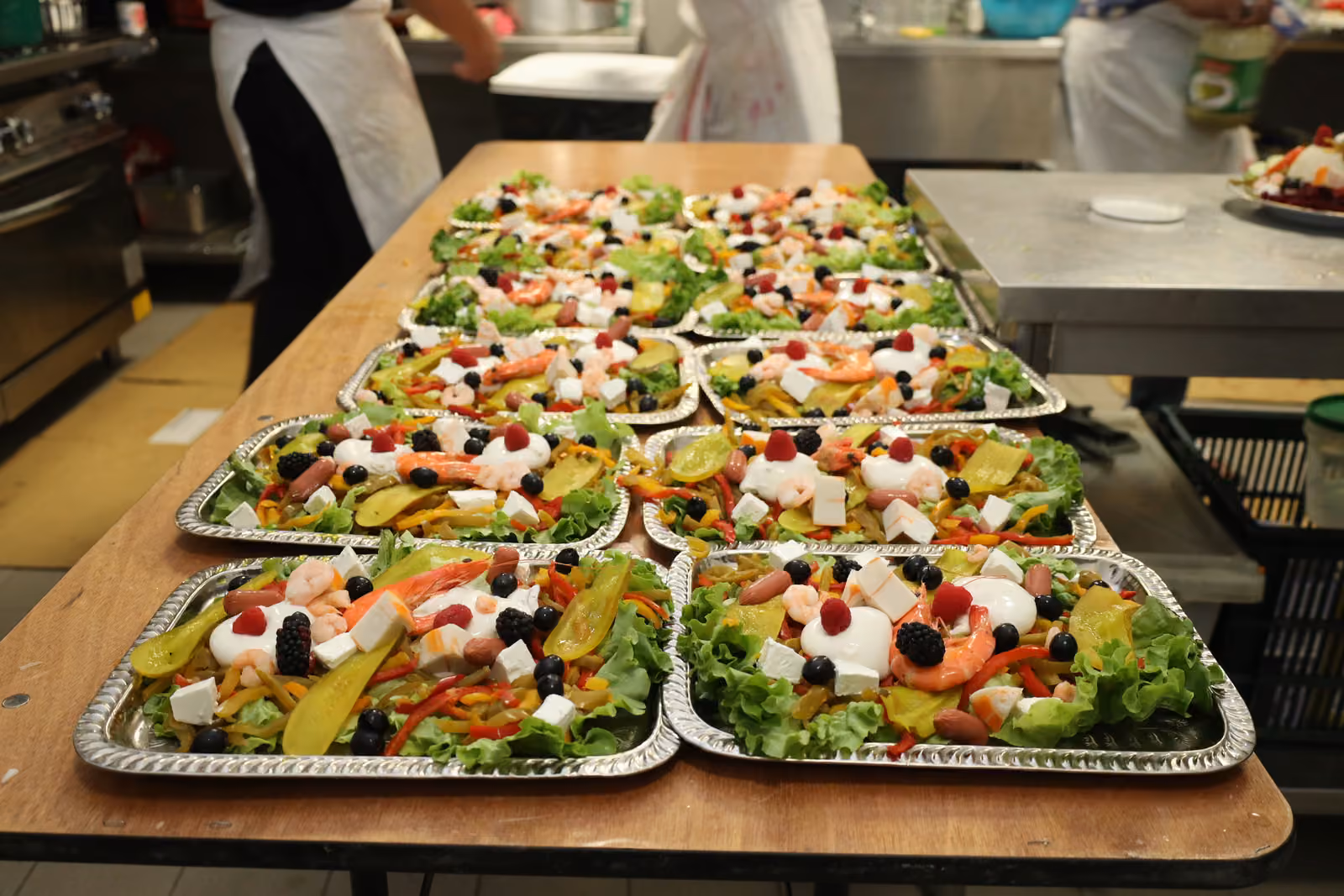 Salades composées en barquettes Rangées de barquettes de salades composées aux crevettes, feta et fruits préparées en cuisine