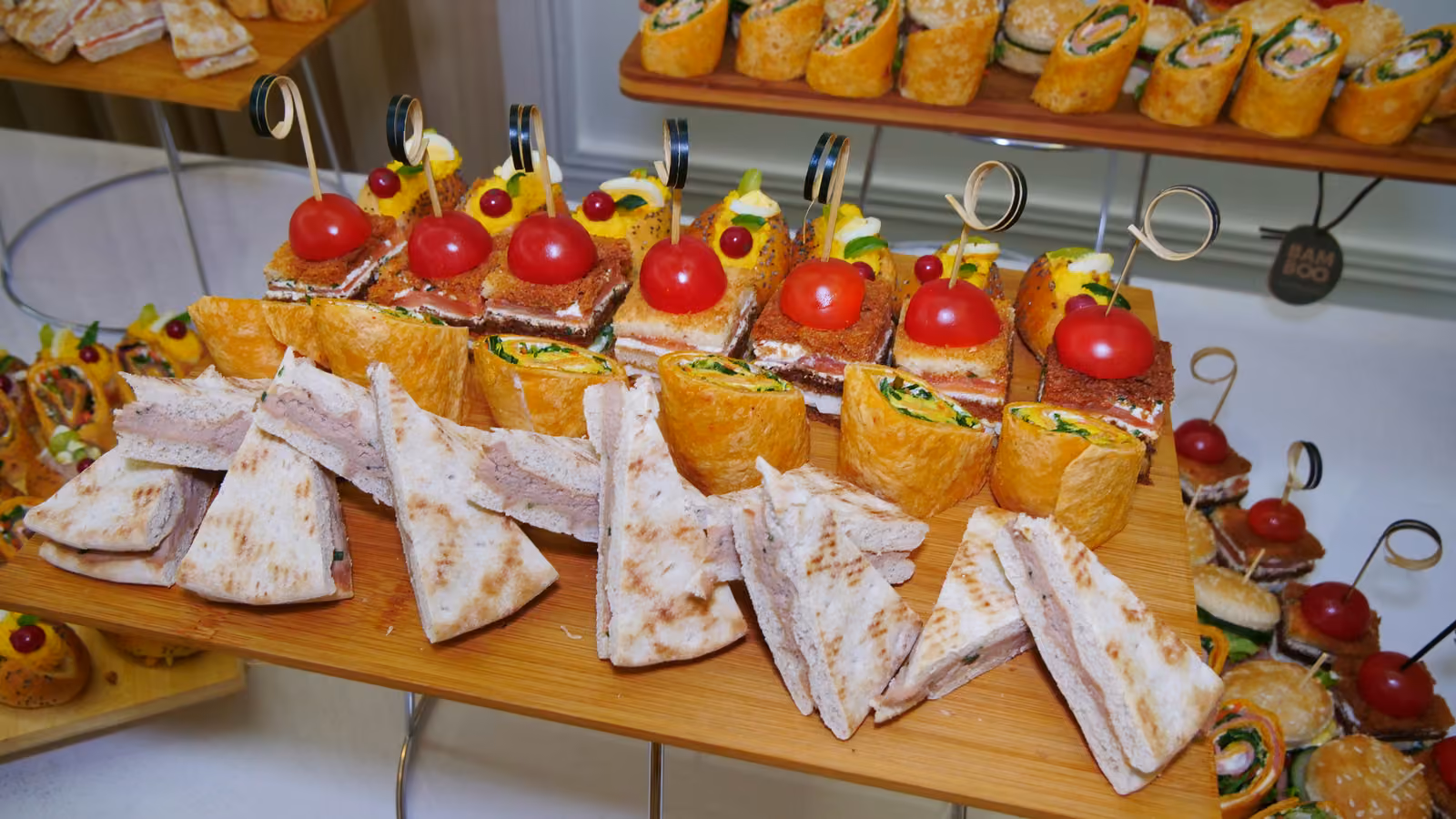 Sandwichs en triangle et wraps Plateau de sandwichs en triangle, wraps et bouchées à la tomate cerise sur présentoir
