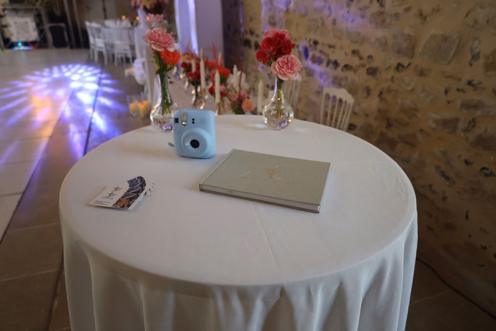 Livre d'or et appareil photo instantané Table ronde du livre d'or de mariage avec appareil photo instantané bleu et roses rouges