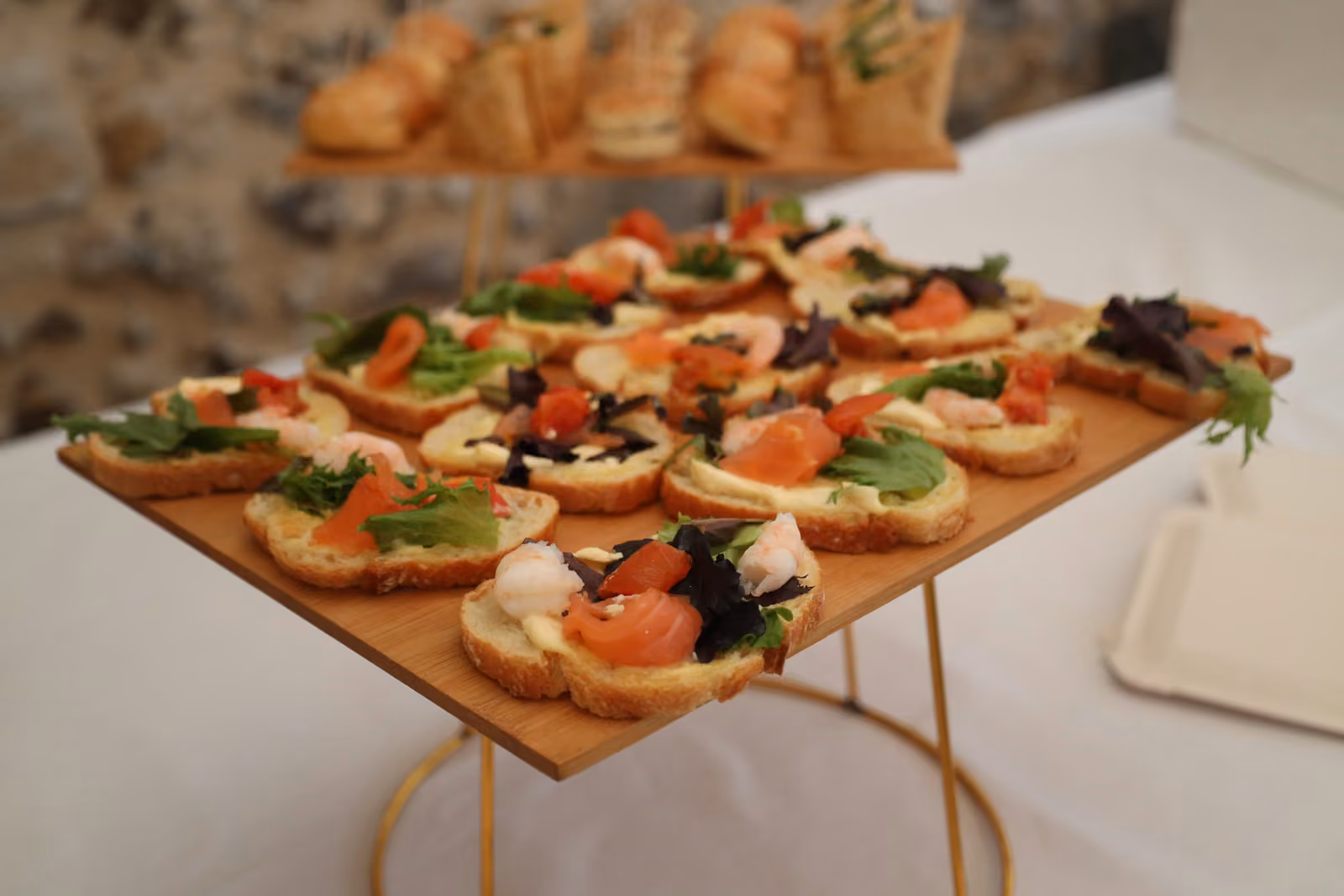 Toasts saumon et tomates confites Toasts au saumon fumé, tomates confites, mozzarella et jeunes pousses sur un plateau en bois