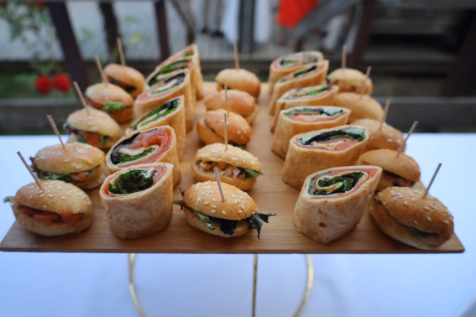 Wraps et mini-burgers sur pics Plateau en bois de wraps roulés et de mini-burgers sur pics, sur un présentoir doré