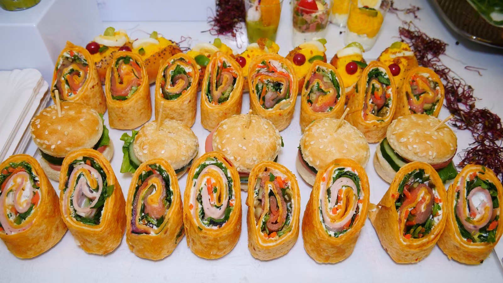 Wraps roulés et mini-burgers Wraps roulés au saumon et aux légumes alignés avec des mini-burgers